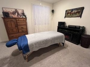 Massage table beside a dresser and electric fireplace